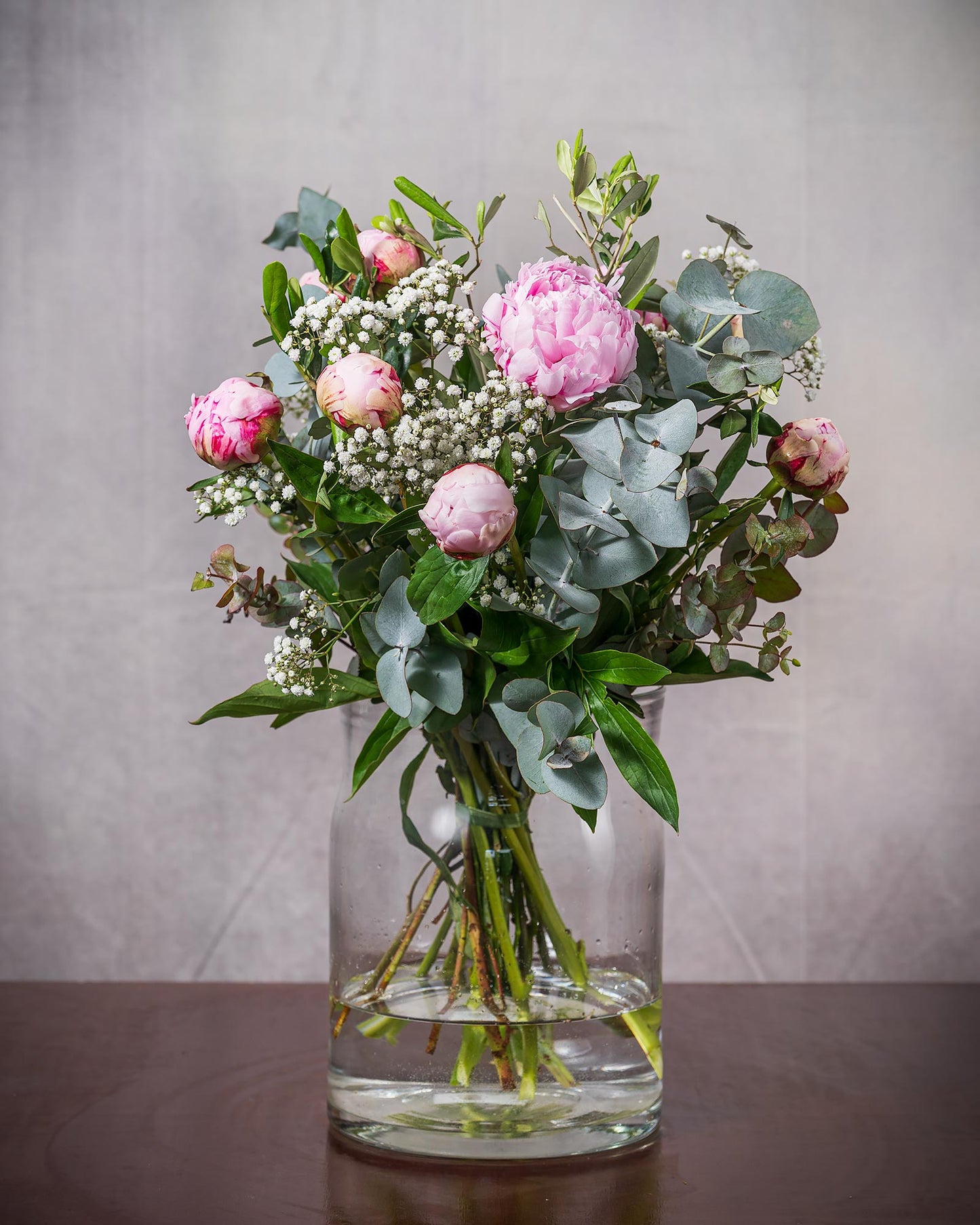 Blumenstrauß mit rosa Pfingstrosen in Glasvase