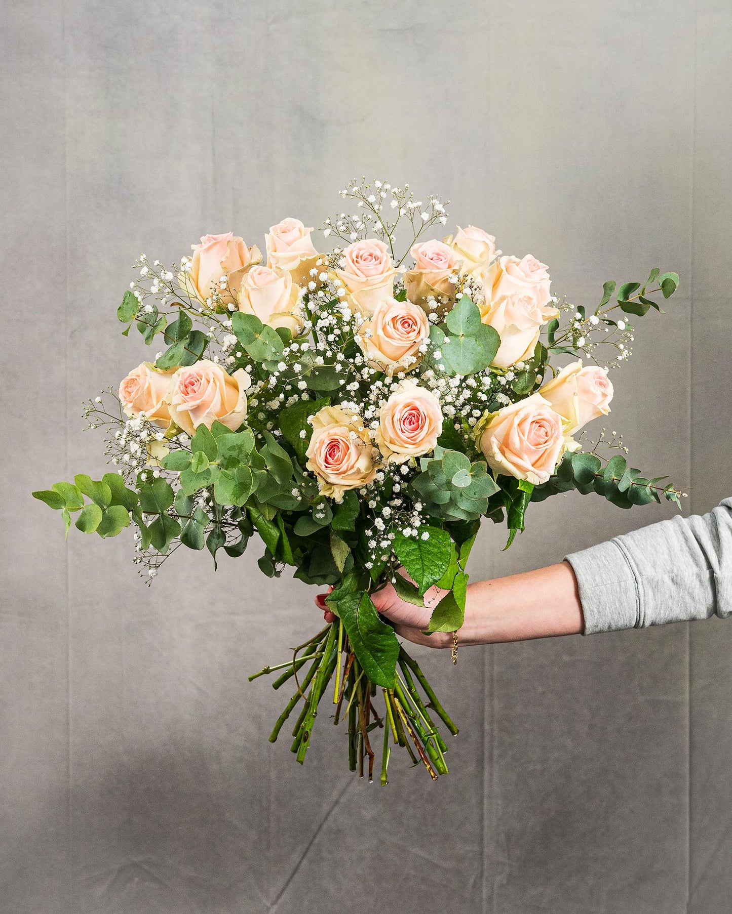 Großer Strauß mit zartrosa Rosen, Schleierkraut und Eukalyptus, von Hand gehalten