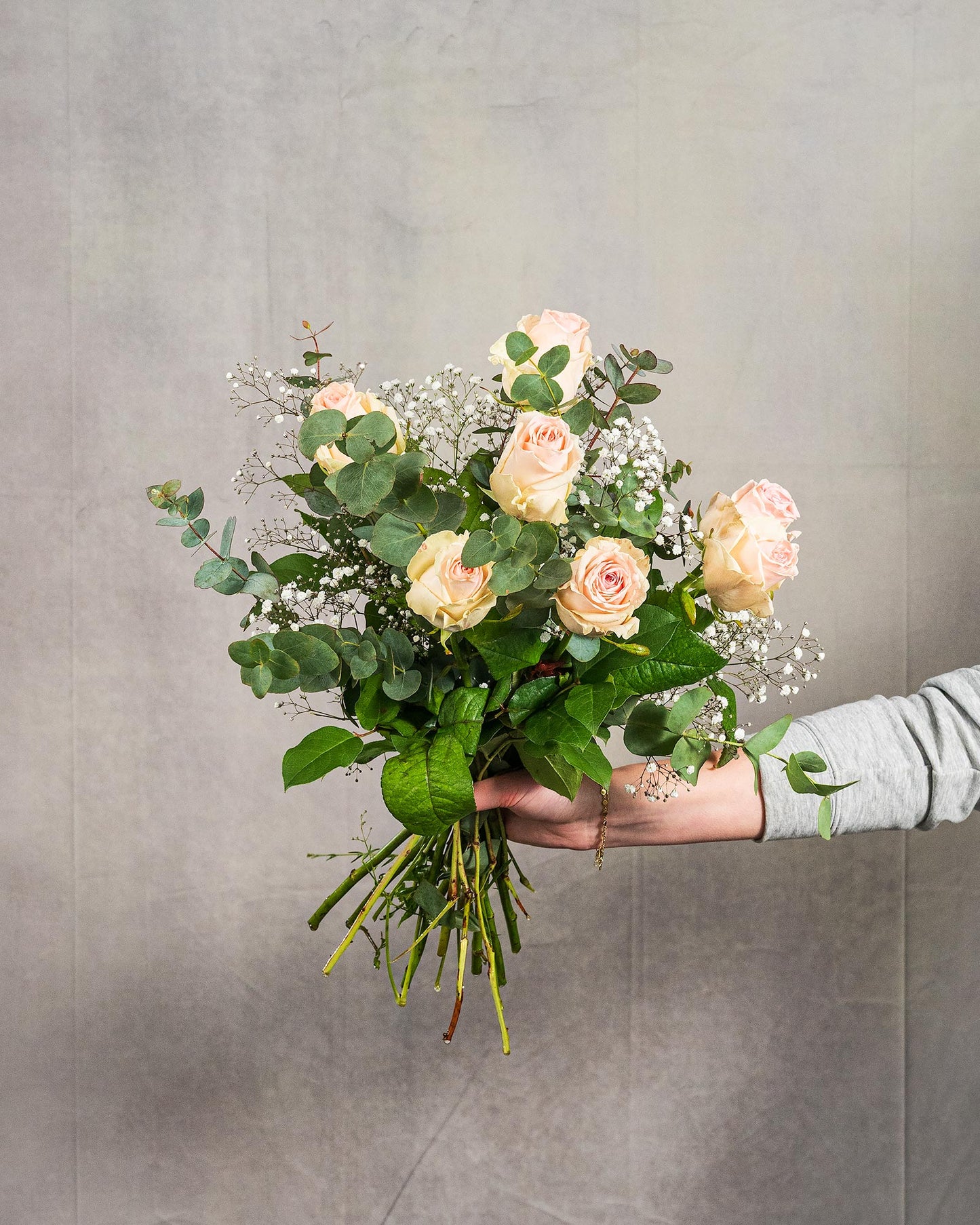 Kleiner Strauß mit pastellrosa Rosen, Schleierkraut und Eukalyptus, von Hand gehalten