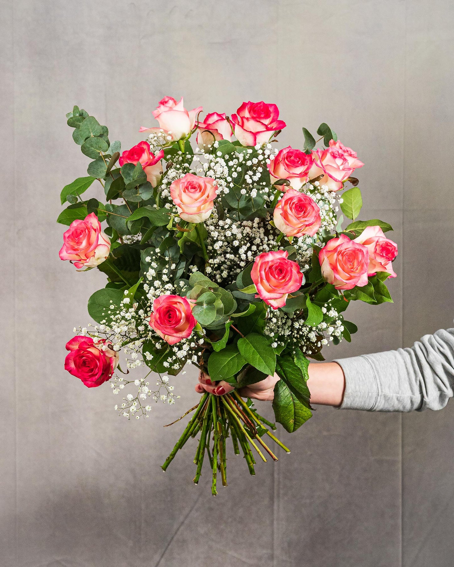 Mittlerer Rosenstrauß mit Eukalyptus und Schleierkraut vor grauem Hintergrund