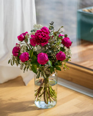 
                  
                    Blumenstrauß mit violetten Pfingstrosen in der Glasvase
                  
                